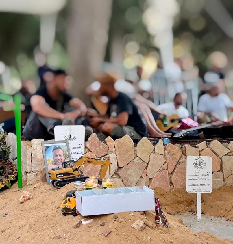Image for the event titled: Friends of Avraham Azulai put a toy excavator and a toy wheel loader on his grave, to commemorate his destruction of homes in Gaza, and his building of homes for Jews-only on Palestinian land in the West Bank